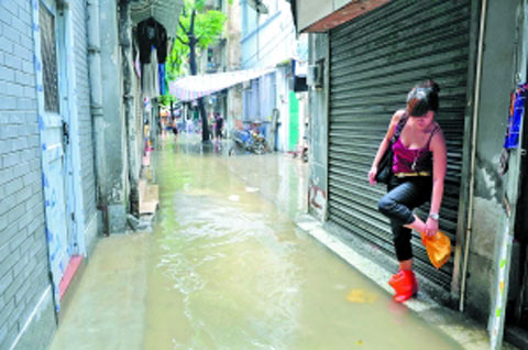 逢源社区一带,一位女士用自制的塑料袋防水鞋突围。(图片来源:广州日报) 逢源社区一带,一位女士用自制的塑料袋防水鞋突围。(图片来源:广州日报)